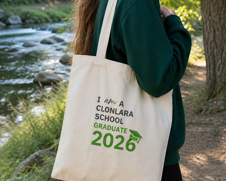 Person holding a tote bag with graduation text in a natural setting

